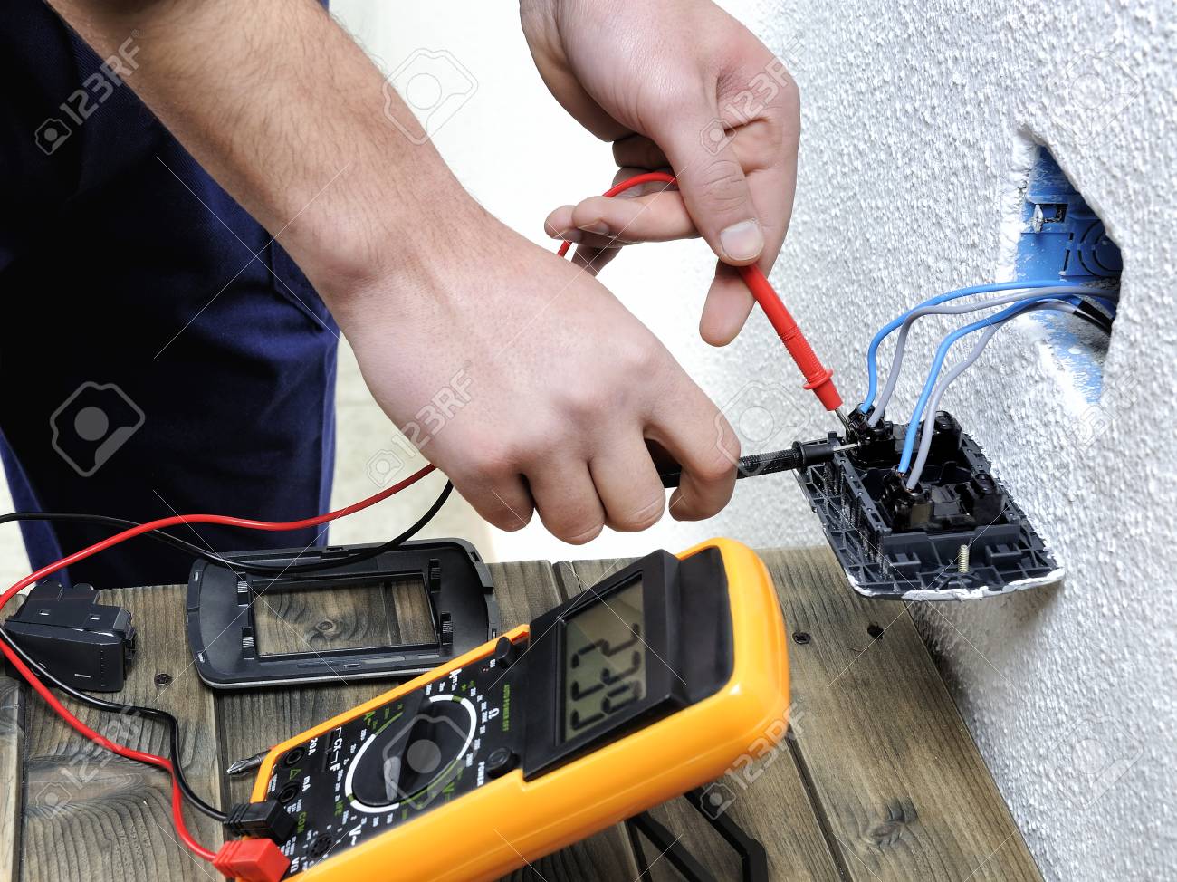 Young electrician at work measures the voltage of a residential electrical installation.